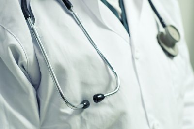 Popiersie mężczyzny, lekarski biały kitel, stetoskop zawieszony na szyi
