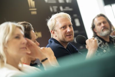 Konferencja twórców filmu na 48. FPFF, kilka osób siedzi na sofie, mikrofon trzyma i wypowiada się Dobromir Dymecki