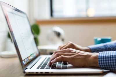 Mężczyzna siedzący przy biurku i piszący na laptopie.