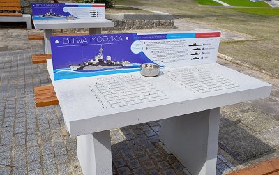 Stół do gry w okręty w plenerze, widoczna tabliczka z napisem 