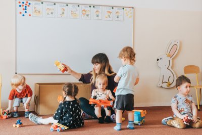 Dzieci w sali z opiekunką i zabawkami