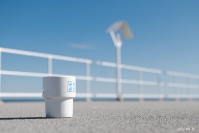 Betonowy pomost na końcu bulwaru Nadmorskiego w Gdyni. Na pierwszym planie biały, barowy kubek z porcelany z niebieskim napisem 