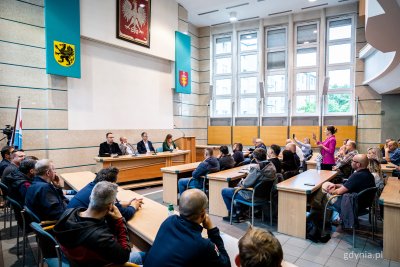 Sala obrad Rady Miasta w Urzędzie Miasta Gdyni, kilkadziesiąt osób siedzi w ławach, na środku Aleksandra Kosiorek, Rafał Geremek, Krzysztof Cieśliński i mecenas.