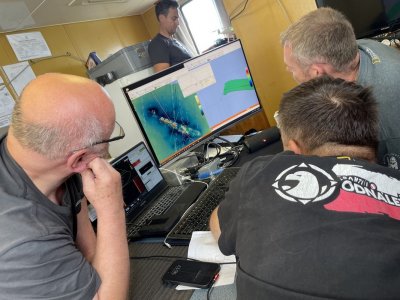 Hydrografowie uczestniczący w 10. ekspedycji „Santi. Odnaleźć Orła” (od lewej): Benedykt Hac, Karol Jacob i Michał Niemkiewicz przyglądający się obrazowi jednego z wraków wyświetlonemu na monitorze