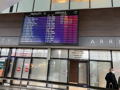 Wnętrze terminala pasażerskiego. Widoczne przejście do hali odlotów, tablica z listą lotów