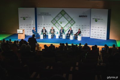 Sala konferencyjna w PPNT Gdynia, widownia pełna ludzi, na scenie biała ścianka Pereł Samorządu, na fotelach siedzi sześciu mężczyzn