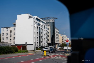 Ulica 3 Maja, samochody, chodnik, biały budynek przy 3 Maja 30, biała ściana