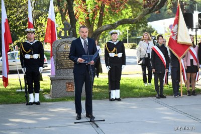 Pomnik Armii Krajowej w Gdyni, przy pomniku żołnierze w mundurach, przemawia do mikrofonu Tomasz Augustyniak