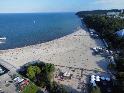 Zdjęcie z drona. Plaża w Śródmieściu Gdyni, letni dzień. Ludzie na plaży, widoczny fragment mariny jachtowej