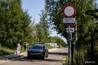 Babie Doły, ulica Zielona, widok w stronę morza, samochód na jezdni, znak zakaz wjazdu, tabliczki informacyjne, słoneczna pogoda