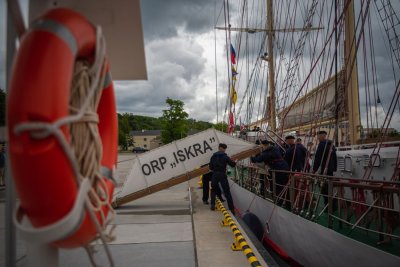 Na zdjęciu na pierwszym planie koło ratunkowe, w tle olinowanie okrętu i członkowie załogi oraz trap z napisem ORP Iskra
