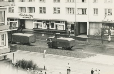 Zdjęcie wykonane z balkonu budynku przy ulicy Władysława IV – widok na tę ulicę, tuż za skrzyżowaniem z ulicą Obrońców Wybrzeża. W centrum ujęte zostały dwie armatki wodne Hydromil I i Hydromil II., na wysokości dawnych Delikatesów na ulicy Władysława IV. Przy dolnej krawędzi fotografii ujęci zostali funkcjonariusze Milicji Obywatelskiej oraz przechodnie. Przy lewym boku widoczny narożnik budynku przy ulicy Obrońców Wybrzeża 5. W tle zabudowa przy ulicy Władysława IV 44, w przyziemiu znajdują się Delikatesy spożywcze –  na osi przerwy pomiędzy witrynami znajduje się neon z nazwą.