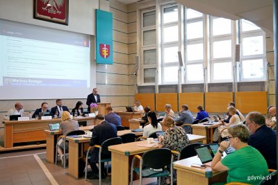 Radni miasta i Mariusz Bzdęga – dyrektor zarządzający ds. kultury i aktywności mieszkańców Urzędu Miasta Gdyni referujący projekt uchwały ws. ustalenia kwoty kalkulacyjnej przypadającej na jednego mieszkańca dzielnicy w naszej gminie podczas sesji Rady Miasta Gdyni (fot. Magdalena Czernek)