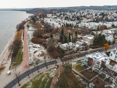Zdjęcie lotnicze fragmentu Orłowa. Widoczny brzeg morza przy plaży, park, działka po byłym klubie Maxim. Budynki przykryte śniegiem