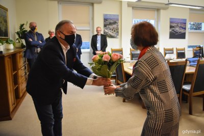 Wojciech Szczurek wręcza bukiet kwiatów Iwonie Torkowskiej, w tle członkowie prezydenckiego kolegium