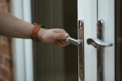 Zbliżenie na dłoń naciskającą na klamkę od drzwi