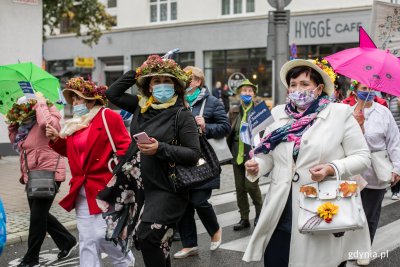 Wielobarwny Pomorski Przemarsz Seniorów ulicami Gdyni. Idą seniorki w kapeluszach z kwiatami i z kolorowymi parasolkami. Fot. Karol Stańczak
