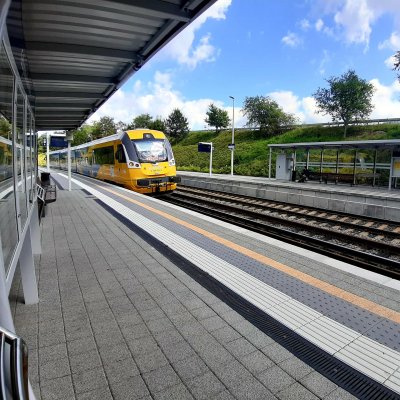 na zdjęciu niebiesko-żółty pociąg wjeżdża na peron