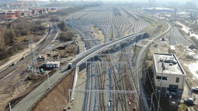 Torowisko dla pociągów towarowych w Gdyni. Widoczne kilkanaście torów, wiadukt, plac budowy. W tle miasto i port