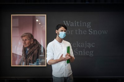 Na zdj. kurator wystawy Maksymilian Bochenek z widoczną w tle fotografią pochodząca z projektu „Czekając na Śnieg” Katarzyny i Marianne Wąsowskich // fot. Bogna Kociumbas
