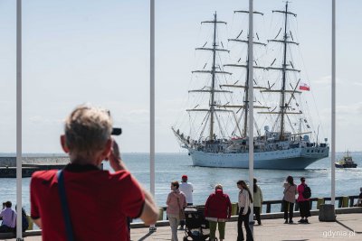 Molo Południowe, Dar Młodzieży wypływa za falochron, ludzie obserwują z nabrzeża, robią zdjęcia telefonem, słoneczna pogoda, widok na zatokę