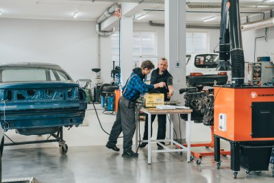 Uczeń i nauczyciel przy samochodzie w szkolonych warsztatach