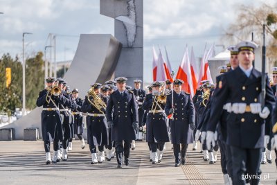 Pomnik Polski Morskiej w Gdyni, słoneczny dzień. Uroczystości wojskowe. Żołnierze w galowych mundurach na placu przed pomnikiem.