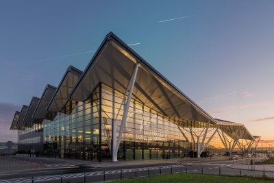 Zachód słońca, budynek terminala T2 Portu Lotniczego Gdańsk. Widoczny fragment szklanej elewacji