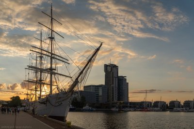 Zachód słońca, molo Południowe w Gdyni. Fragment nabrzeża, zacumowany Dar Pomorza, w tle Sea Towers i Śródmieście.