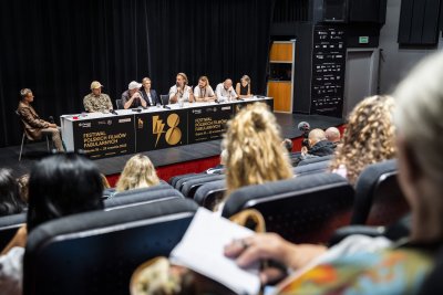 Sala kinowa w Gdyńskim Centrum Filmowym, widownia w fotelach, na scenie stół konferencyjny, siedzą aktorzy, twórcy i reżyser filmu, odpowiadają na pytania przez mikrofon