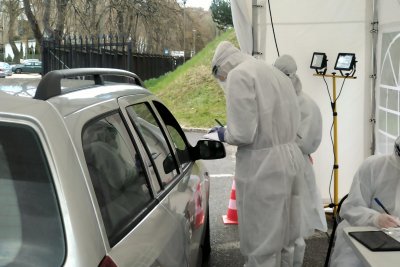 Dwóch medyków, w specjalnych kombinezonach, pobiera wymaz na obecność COVID-19 od pacjenta w samochodzie. To tak zwane punkty „Drive&Go-Thru”. Mat. prasowe.