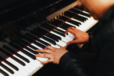 Klawiatura pianina. Widoczne męskie dłonie grające na instrumencie.