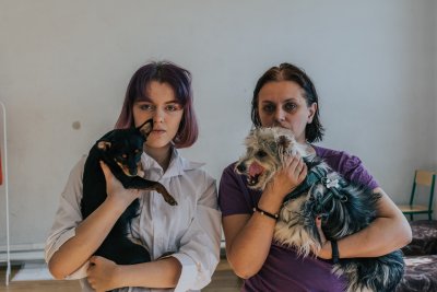 Kobieta i nastolatka trzymają na rękach psy.