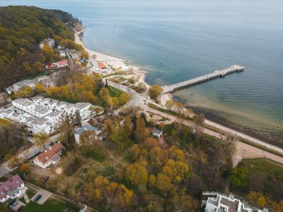 Lotnicze zdjęcie fragmentu Orłowa. Widoczna zatoka, molo, plaża, promenada, ulica i zabudowania