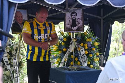 Cmentarz. Urna, zdjęcie Janusza Kupcewicza, mężczyzna w koszulce Arki Gdynia obok