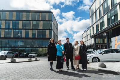 Biurowce Łużycka Office Park, widocznych kilka budynków, ulica, zaparkowane samochody, na środku drogi wewnętrznej do zdjęcia pozują Justyna Patyk, Aleksandra Kosiorek, Rafał Proczek, Izabela Disterheft i Anna Kacprzak