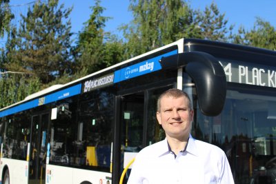 Lech Żurek pozuje do zdjęcia, za jego plecami gdyński autobus.