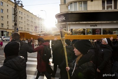 na zdjęciu ludzie idący z krzyżem ulicą