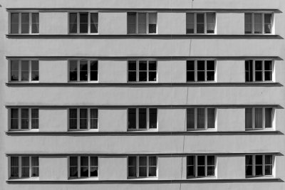 Zdjęcie szeregu okien na ścianie modernistycznego budynku. Czarno-biała fotografia