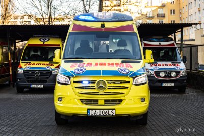 Plac przy Miejskiej Stacji Pogotowia Ratunkowego, żółta karetka pogotowia, w tle dwie karetki i wiata