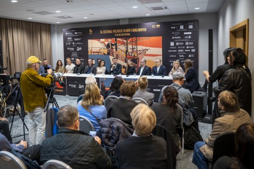 Sala konferencyjna, ścianka FPFF w Gdyni, grupa osób siedząca za stołem