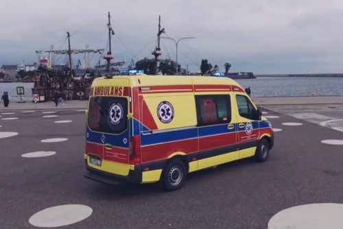 Molo Południowe, plac, widoczna marina i statek, na pierwszym planie źółta karetka