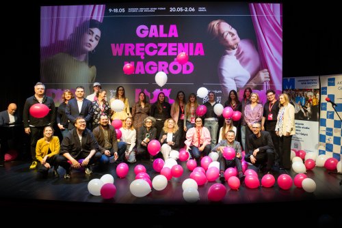 na zdjęciu uśmiechnięci ludzie na scenie z białymi i różowymi balonami