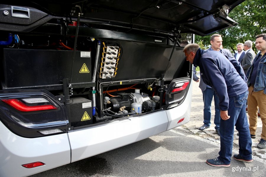 Uczestnicy prezentacji oglądają tył autobusu wodorowego. Jeden z mężczyzn nachyla się i zagląda do środka // fot. Przemysław Kozłowski