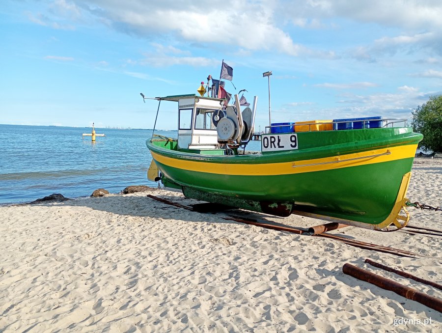 Kuter rybacki stojący na plaży, w tle morze i pogodne niebo