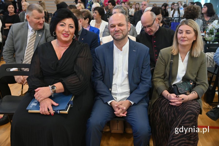 Kobiety i mężczyźni siedzący na krzesłach w szkolnej hali gimnastycznej