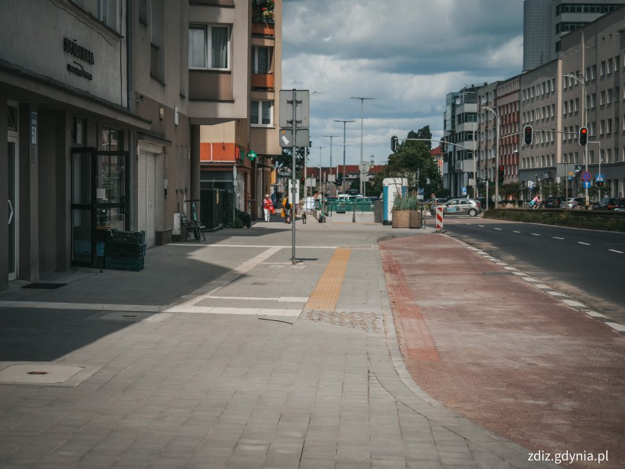 Chodnik na ul. Śląskiej po remoncie, widoczne budynki, samochody, oznakowanie