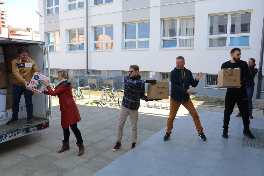 Grupa pięciu osób rozpakowuje przyczepę tworząc tzw. łańcuch rąk. 