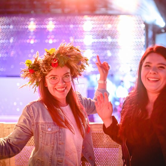 Festiwal Cudawianki. Dwie kobiety podczas koncertu, jedna z nich ma na głowie wianek z kwiatów