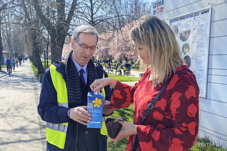 Radny Zenon Roda w roli wolontariusza i mieszkanka wrzucająca datek do puszki